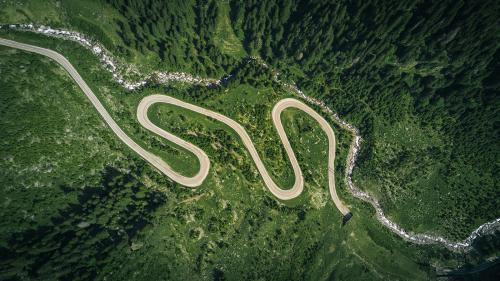 An aerial view of a road winding through a forested landscape.