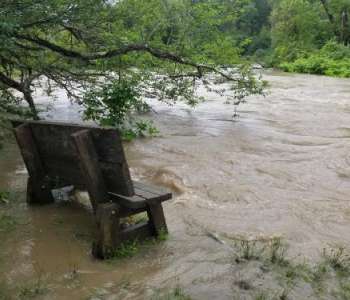 A bench stands amid the water of a flooding river. A bench stands amid the water of a flooding river.